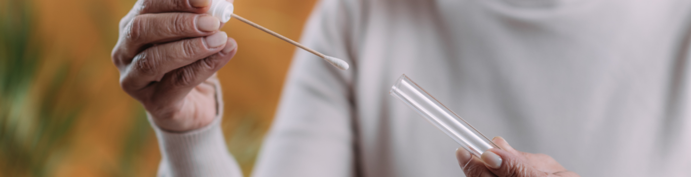 A physician holds a cotton swab and test vial