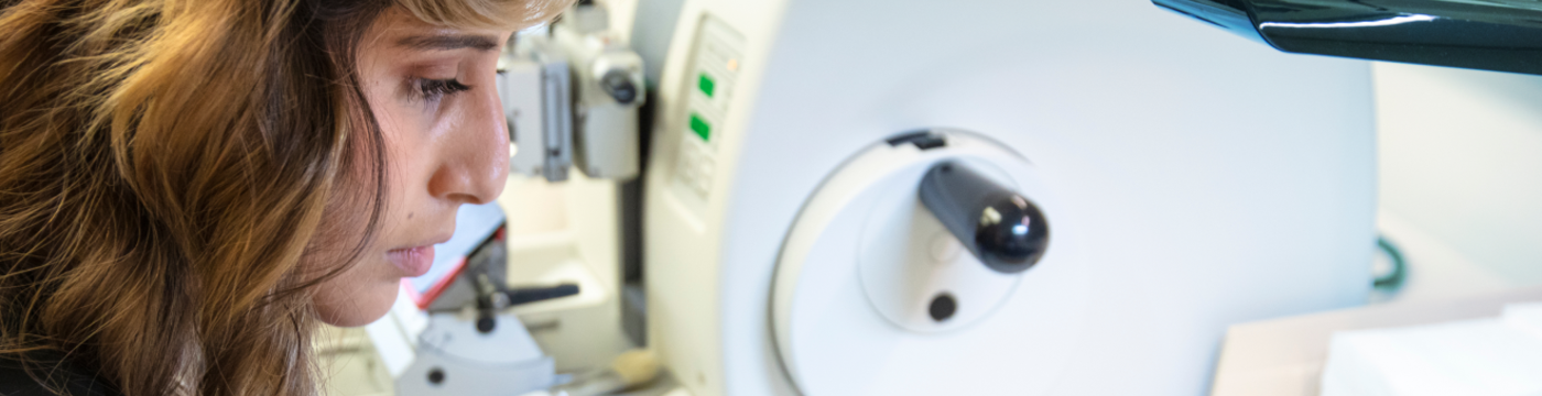 A physician looks at a clinical sample through a powerful microscope