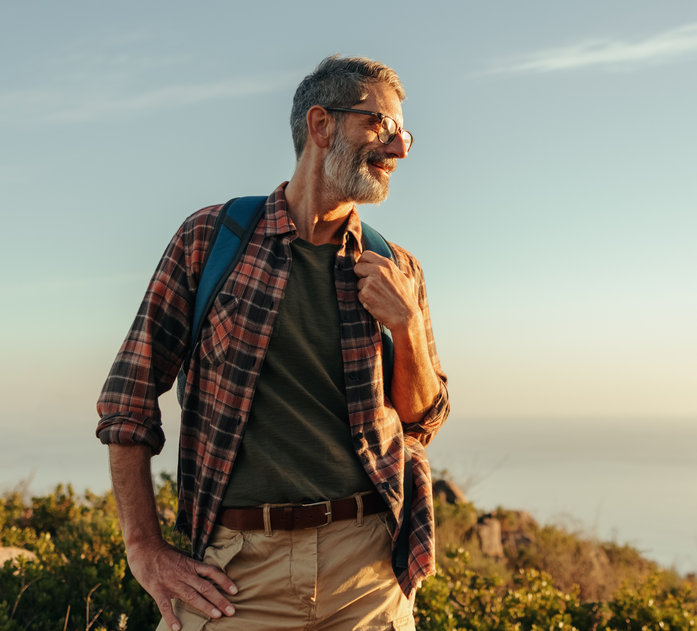 An active older man is outside at sunrise and looking into the distance